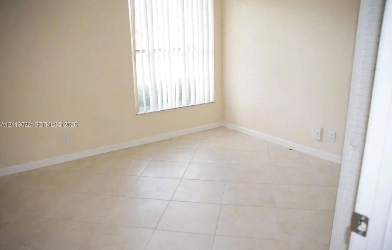 Neutral-toned ceramic tile flooring, vertical window blinds, and crisp off-white wall finishes Neutral-toned ceramic tile flooring, vertical window blinds, and crisp off-white wall finishes