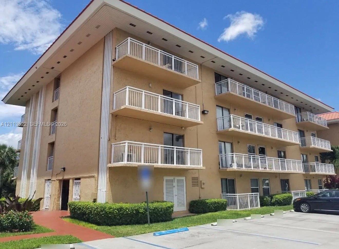 Multi-story exterior featuring a textured facade, stacked balconies with white railings, and a wide roof overhang Multi-story exterior featuring a textured facade, stacked balconies with white railings, and a wide roof overhang