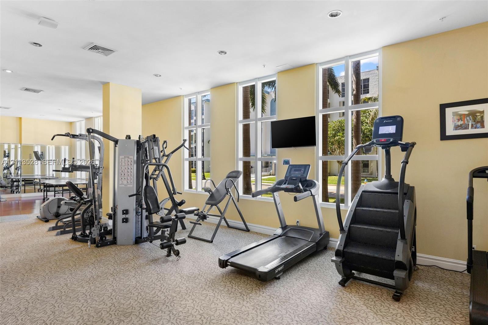 Fitness center featuring wall-to-wall carpeting, floor-to-ceiling windows, and recessed ceiling lighting