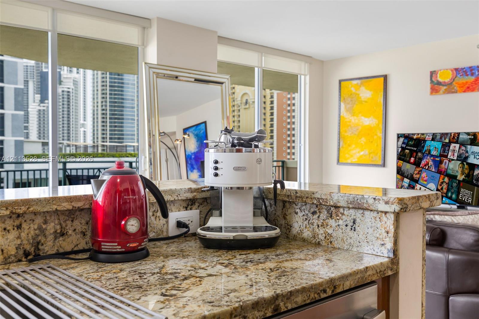 Kitchen featuring stone countertops with a breakfast bar, stainless steel appliance, and floor-to-ceiling windows