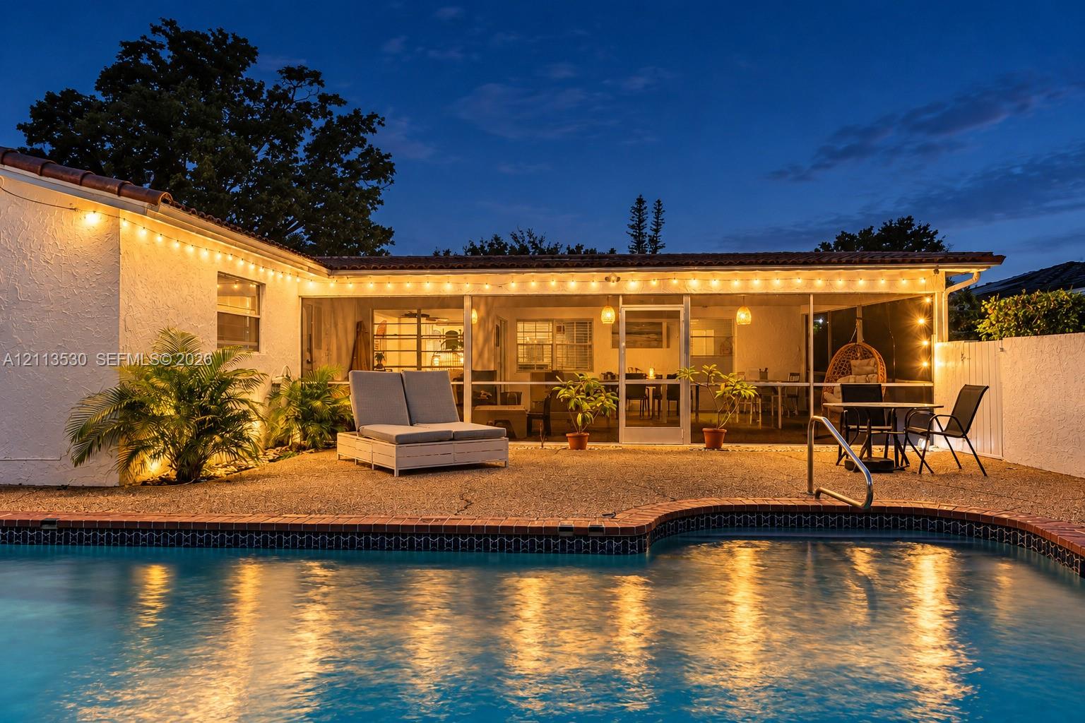 Exterior swimming pool with brick coping, screened-in patio, and aggregate stone hardscaping