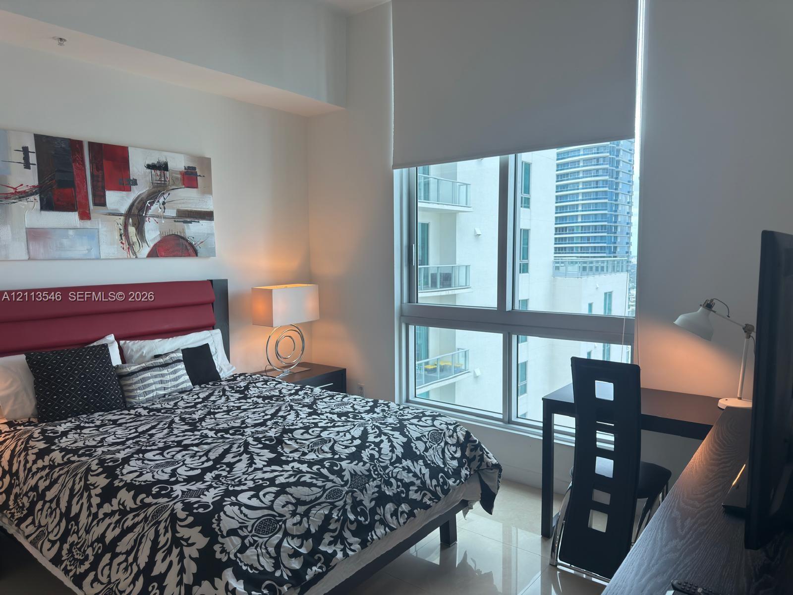 Floor-to-ceiling windows with roller shades and polished tile flooring