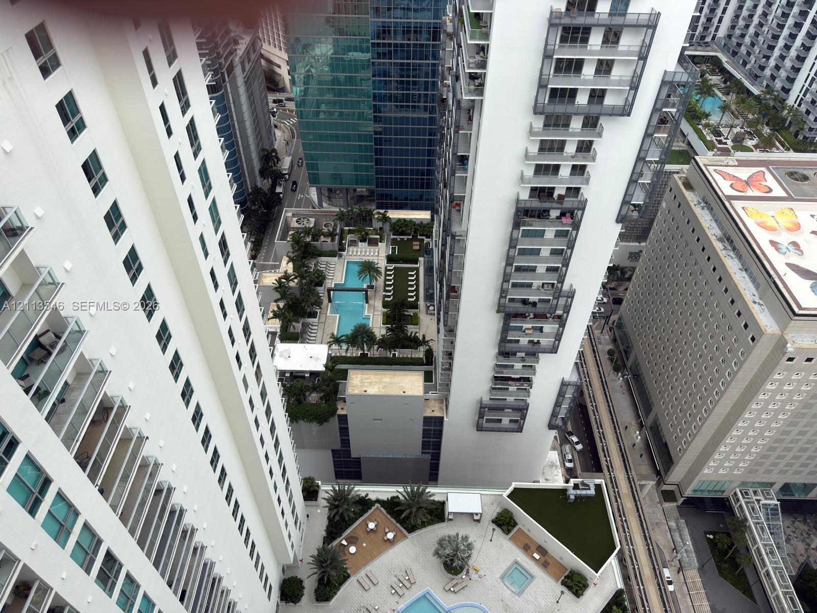 High-rise urban perspective featuring tiered balconies, a ground-level swimming pool, and an elevated terrace with manicured landscaping High-rise urban perspective featuring tiered balconies, a ground-level swimming pool, and an elevated terrace with manicured landscaping