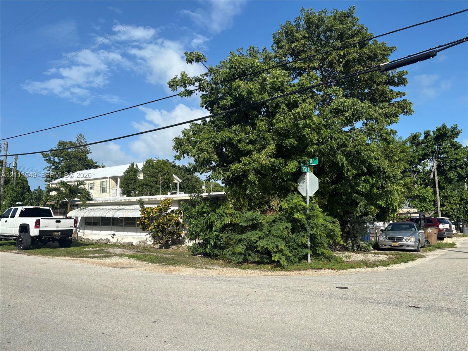 Exterior view of property featuring a multi-level structure with a metal roof and mature trees on a corner lot