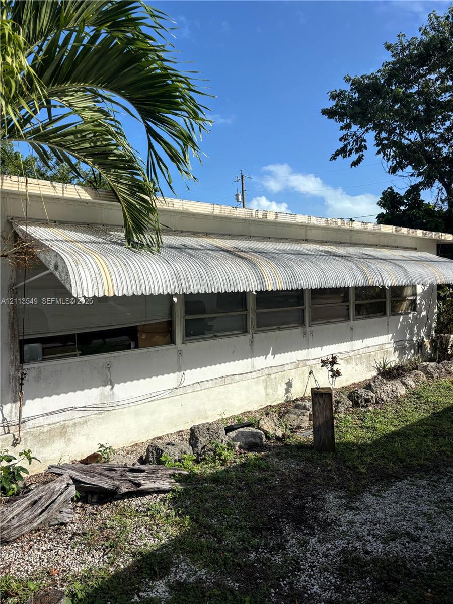 Exterior profile featuring a metal-sided facade, horizontal sliding windows, and a corrugated metal awning