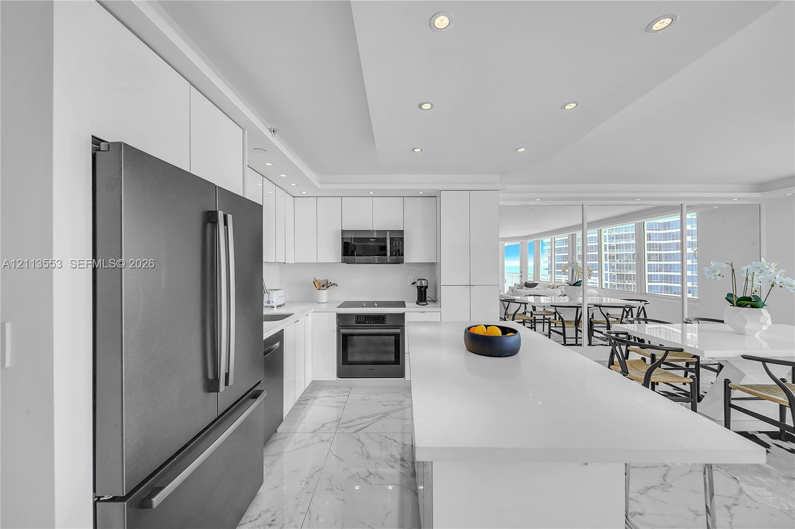 Kitchen featuring flat-panel white cabinetry, a center island with a stone-finish countertop, stone-finish flooring, recessed lighting, and stainless steel appliances