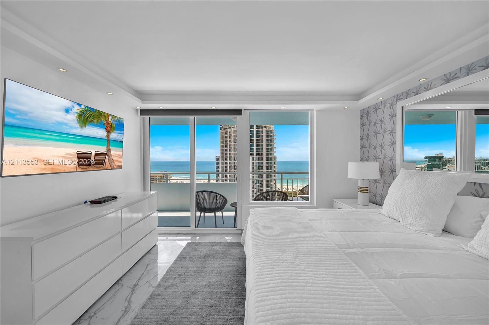 Sliding glass doors opening to a private balcony, large-format stone-finish flooring, recessed lighting, and expansive window wall