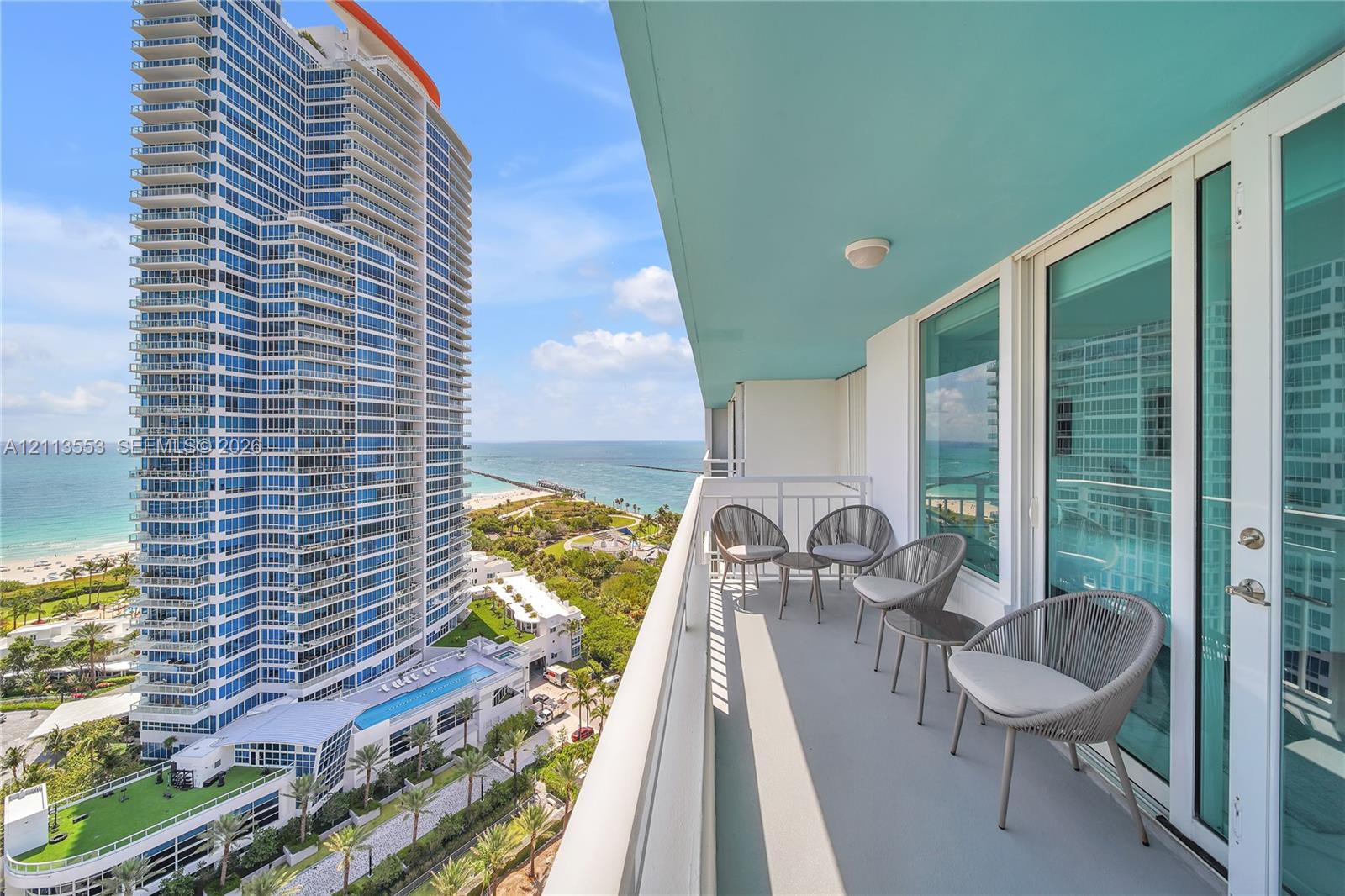 Covered balcony with a solid surface floor, white metal railing, and floor-to-ceiling glass sliding doors