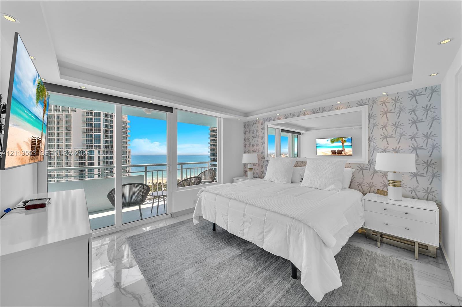 Floor-to-ceiling glass sliding doors, stone-finish flooring, recessed ceiling lighting, and expansive window wall with oceanic backdrop