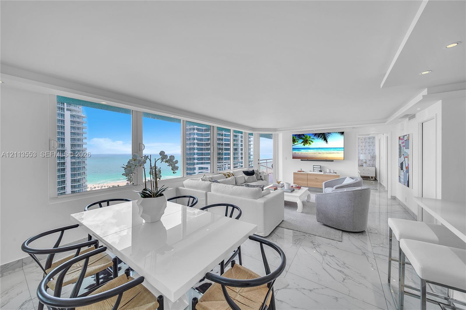 Open-concept interior featuring floor-to-ceiling windows, natural stone-finish flooring, recessed lighting, and expansive ocean scenery Open-concept interior featuring floor-to-ceiling windows, natural stone-finish flooring, recessed lighting, and expansive ocean scenery