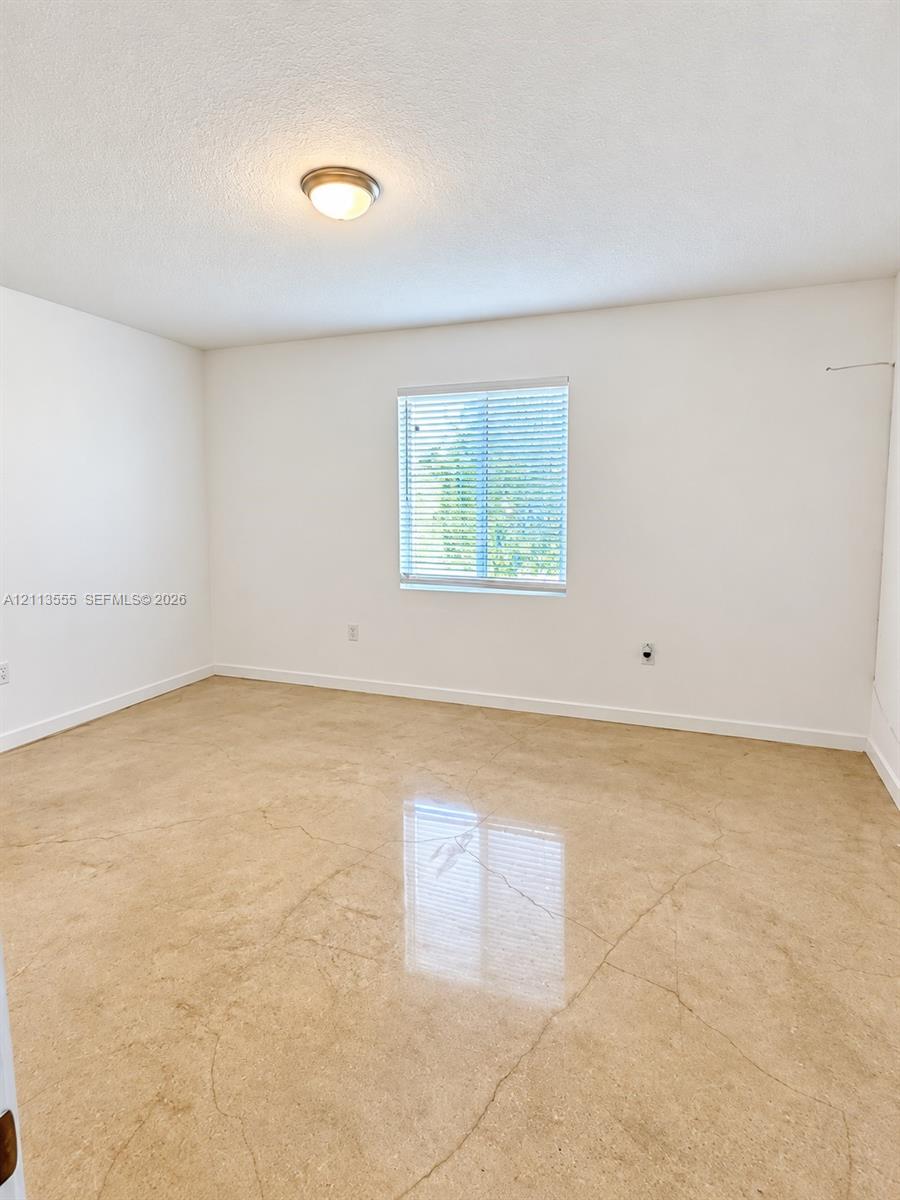 Neutral interior space featuring polished concrete flooring, white walls, and a single-light flush-mount ceiling fixture with an integrated window blind