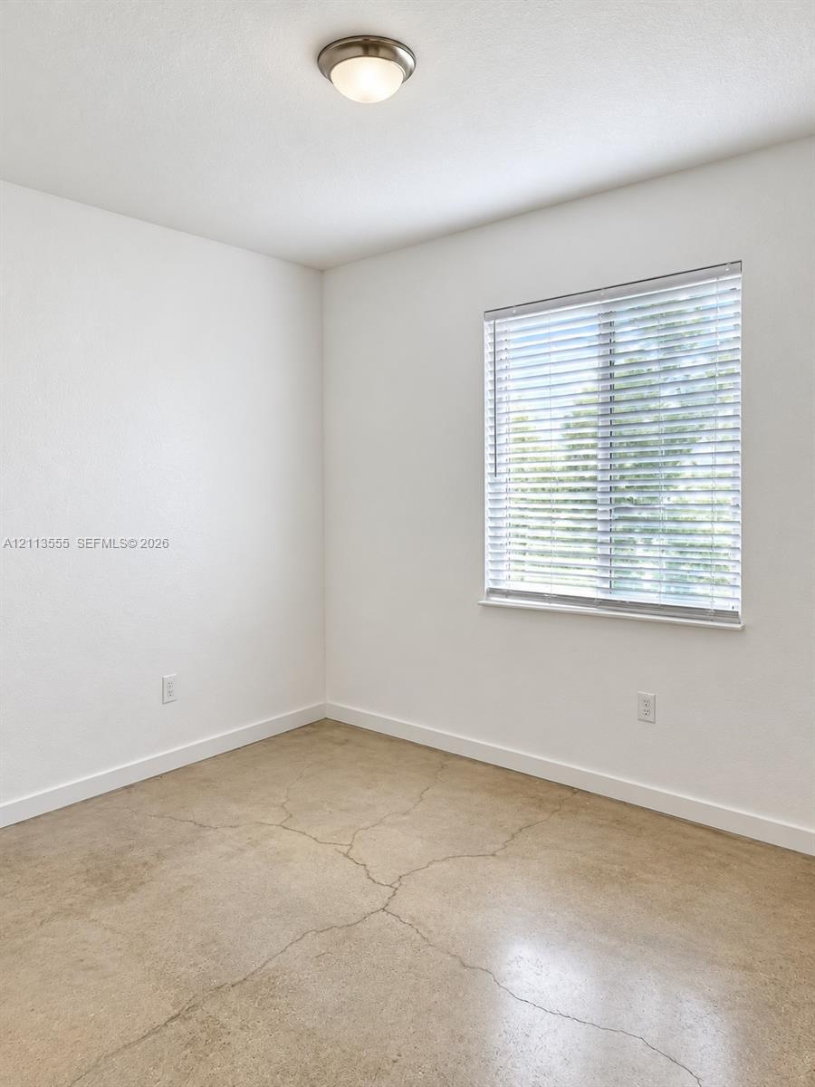 Polished concrete flooring, neutral wall finish, horizontal window blinds, and a semi-flush mount ceiling fixture