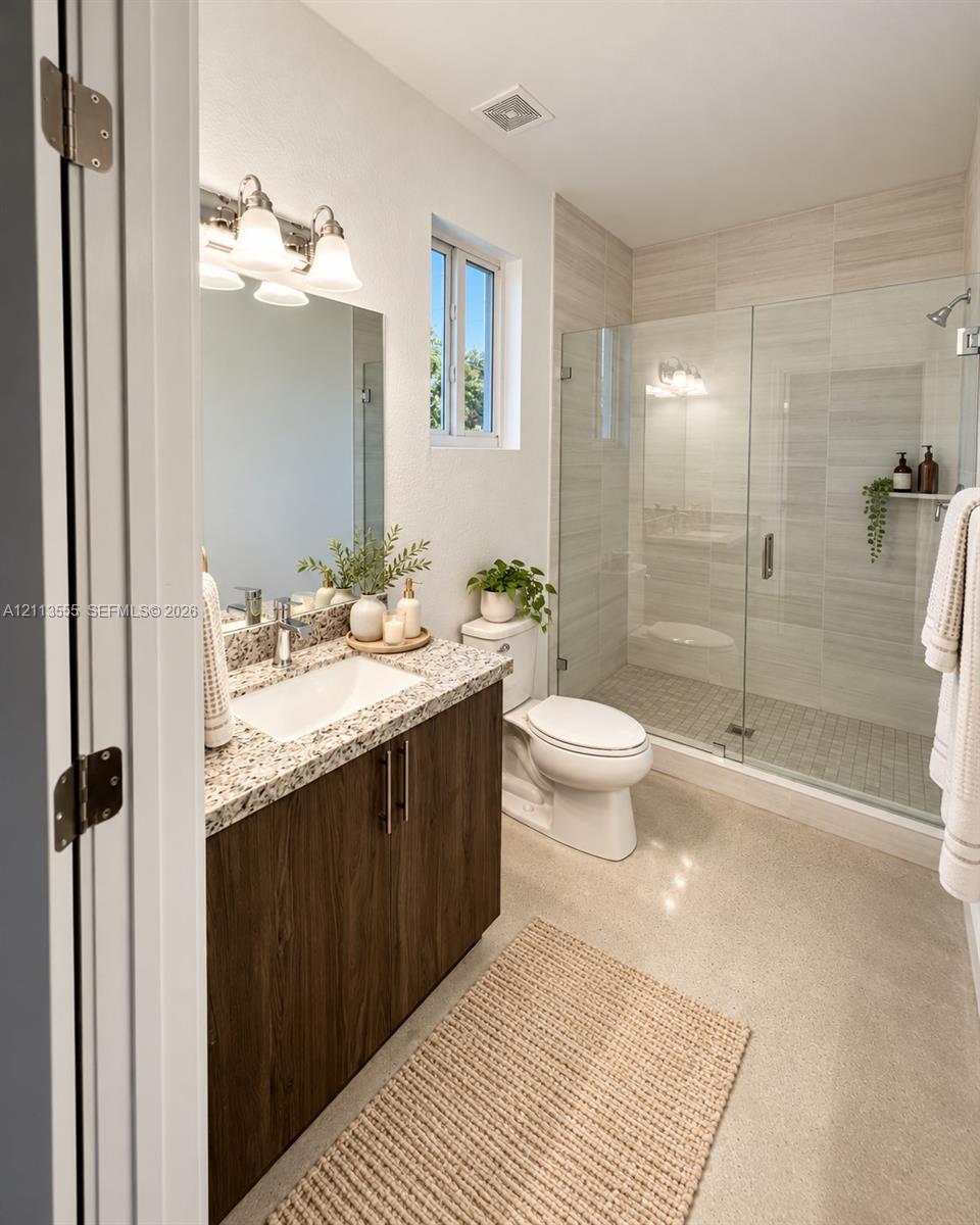 Bathroom featuring a dark wood-finish vanity with a stone countertop, an integrated rectangular sink, a glass-enclosed walk-in shower with tile surround, and a three-light wall-mounted vanity fixture