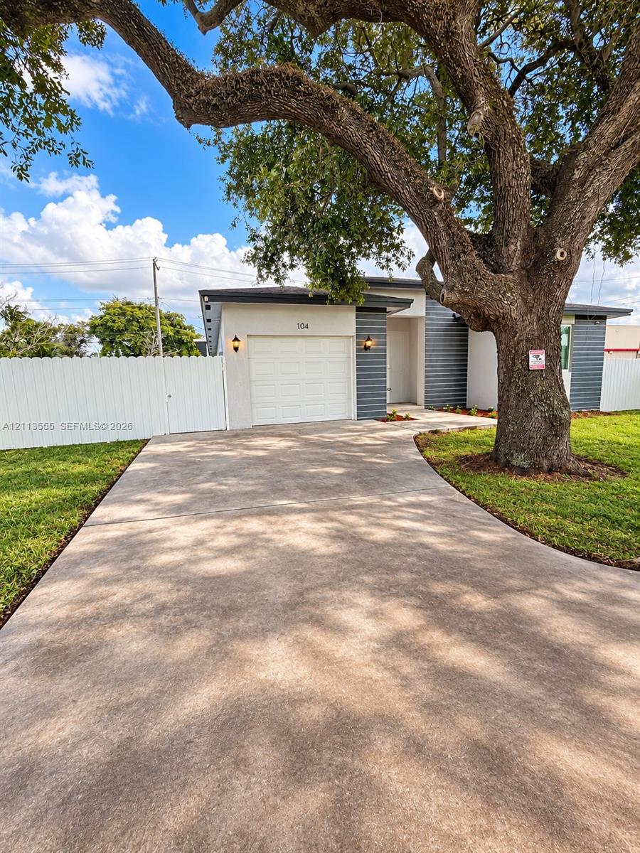 Exterior facade featuring horizontal siding and a single-car garage, concrete driveway, and white privacy fencing Exterior facade featuring horizontal siding and a single-car garage, concrete driveway, and white privacy fencing