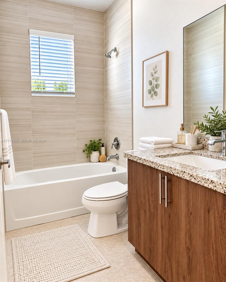 Bathroom featuring floor-to-ceiling textured tile surround, built-in vanity with wood-finish cabinetry, stone-composite countertop with integrated sink, and an inset mirror