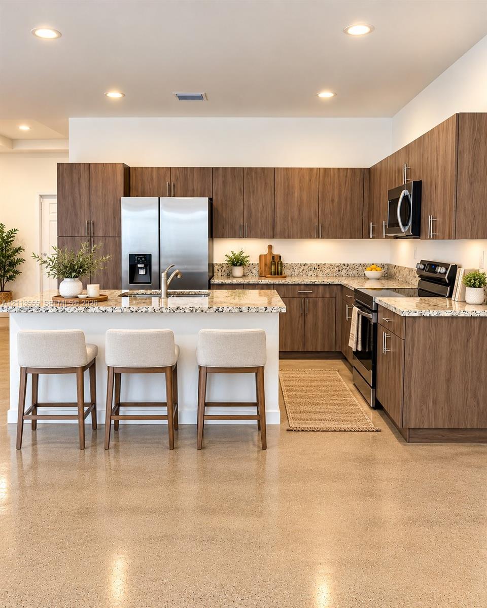 Kitchen featuring wood-finish cabinetry, stone-surface countertops, polished concrete flooring, stainless steel appliances, and recessed lighting Kitchen featuring wood-finish cabinetry, stone-surface countertops, polished concrete flooring, stainless steel appliances, and recessed lighting