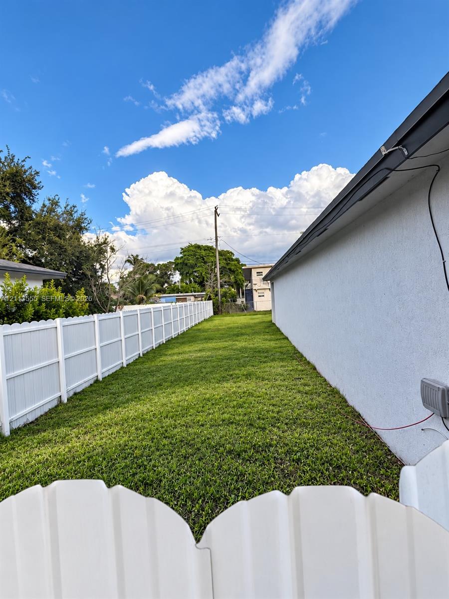 Side yard featuring a white vinyl privacy fence and a manicured lawn