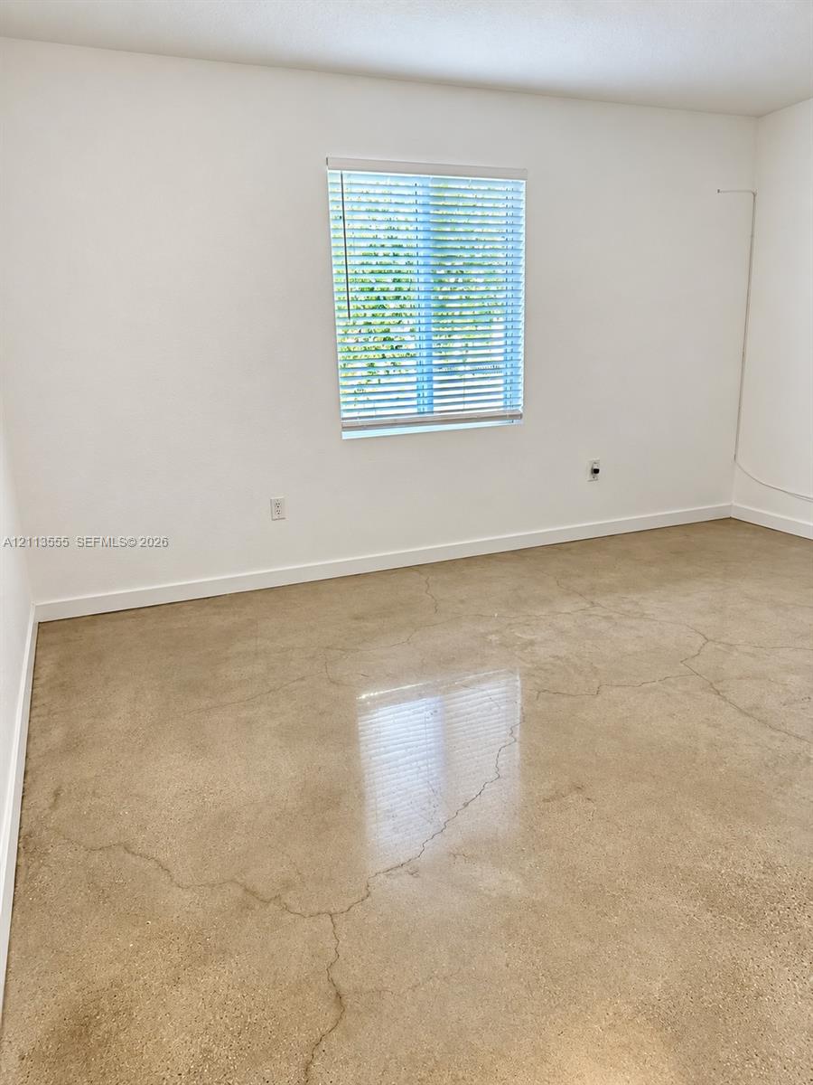 Polished concrete flooring, neutral wall finishes, and a single-pane window with installed horizontal blinds