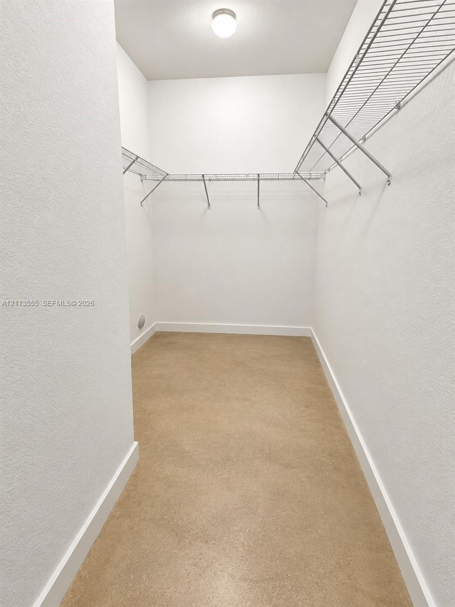 Walk-in closet featuring neutral walls, wire shelving, a ceiling-mounted light fixture, and solid-surface flooring