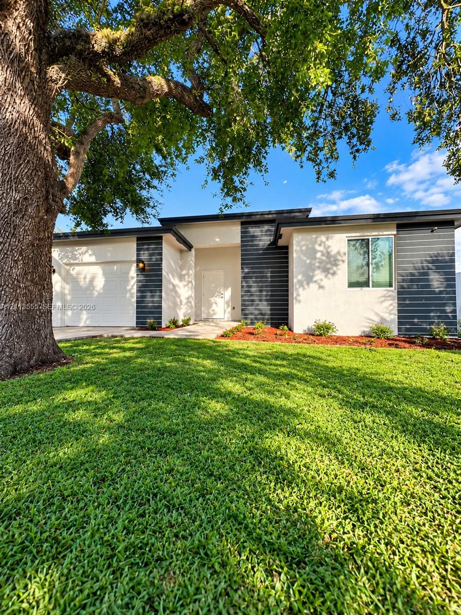 Single-story exterior featuring a stucco and horizontal siding facade, flat roofline, attached garage, and mature tree canopy Single-story exterior featuring a stucco and horizontal siding facade, flat roofline, attached garage, and mature tree canopy