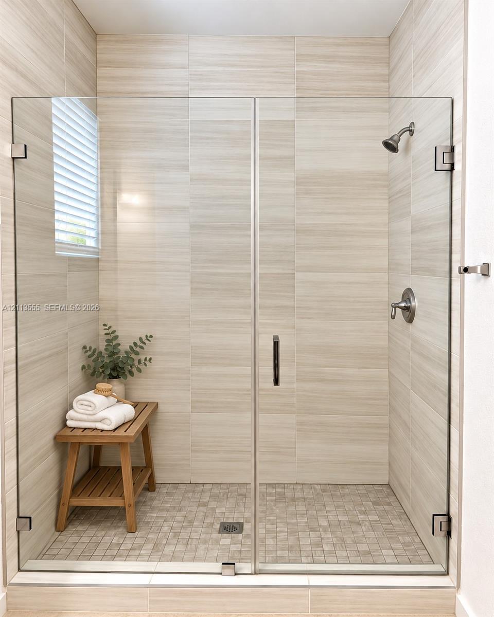 Walk-in shower featuring floor-to-ceiling large-format tile walls, mosaic tile flooring, a frameless glass enclosure, and brushed nickel hardware