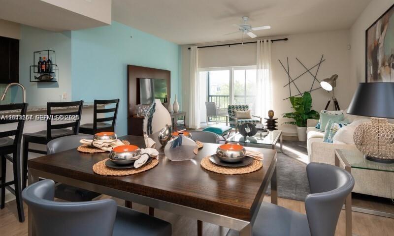 Open-concept living space featuring wood-finish flooring, recessed lighting, a ceiling fan, and sliding glass doors leading to a balcony