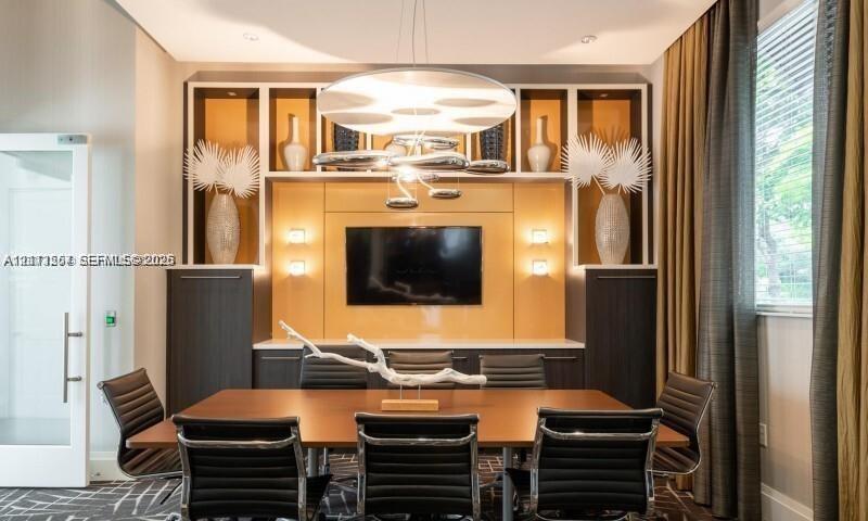Custom floor-to-ceiling built-in cabinetry featuring integrated recessed lighting, high-contrast wood-grain finishes, and a contemporary multi-tiered overhead chandelier