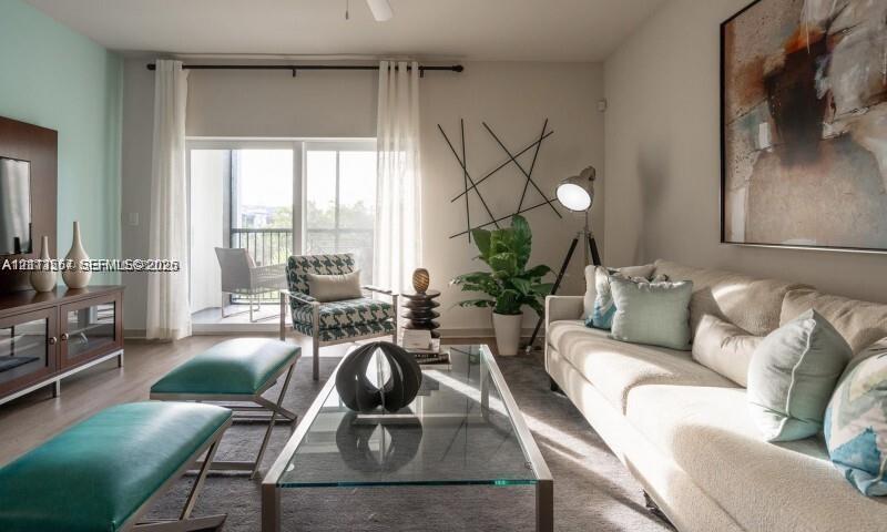 Living area featuring wood-finish flooring, a wall-mounted media console, and sliding glass doors with direct access to a private balcony