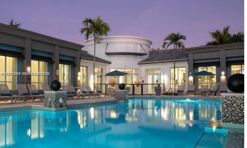 Swimming pool featuring decorative mosaic tile pillars, expansive paved patio, and multi-pane glass doors