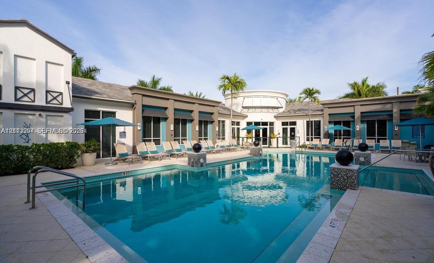 Swimming pool with tiled coping, stone-accented columns, paved pool deck, and surrounding multi-structure exterior