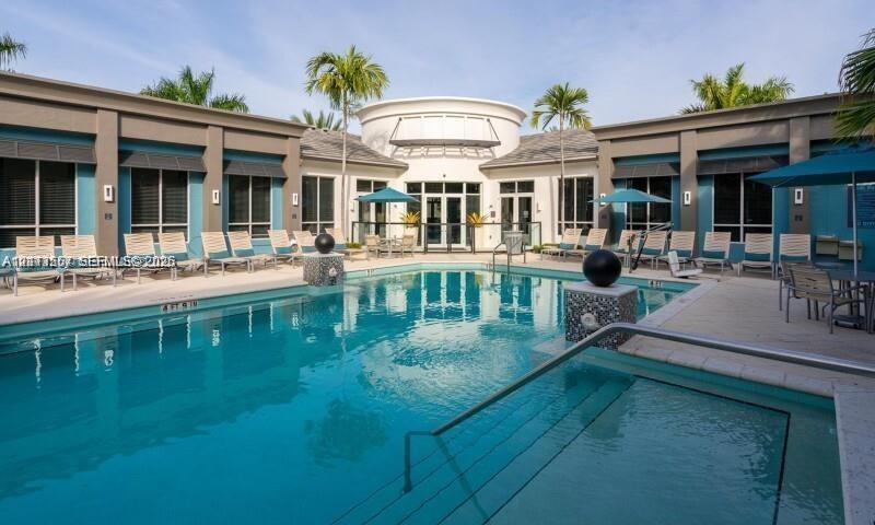 Swimming pool and spa area with a stone-accented water feature, sun deck, and mature palm trees