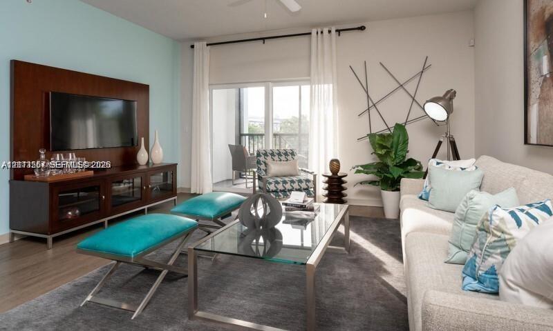 Living area featuring wood-finish flooring, a built-in wood-veneer media wall, a ceiling fan, and sliding glass doors with access to a balcony