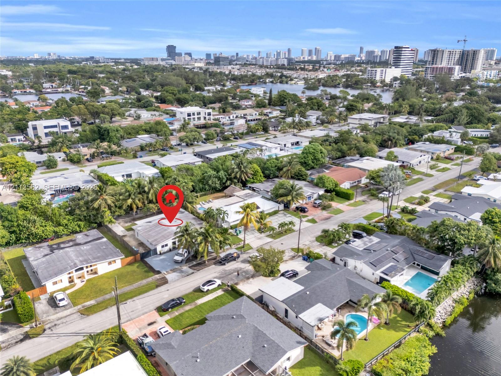 Aerial perspective featuring residential property with low-pitched roofing, paved driveway, and established palms, set within a coastal community