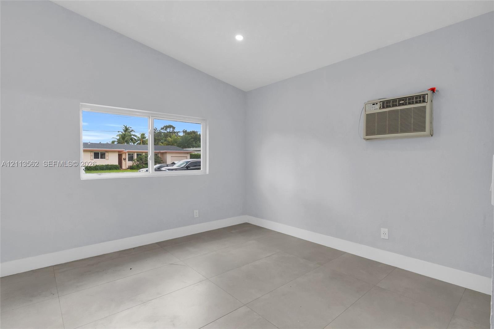 Vaulted ceiling, large-format tile flooring, recessed lighting, and a horizontal sliding window