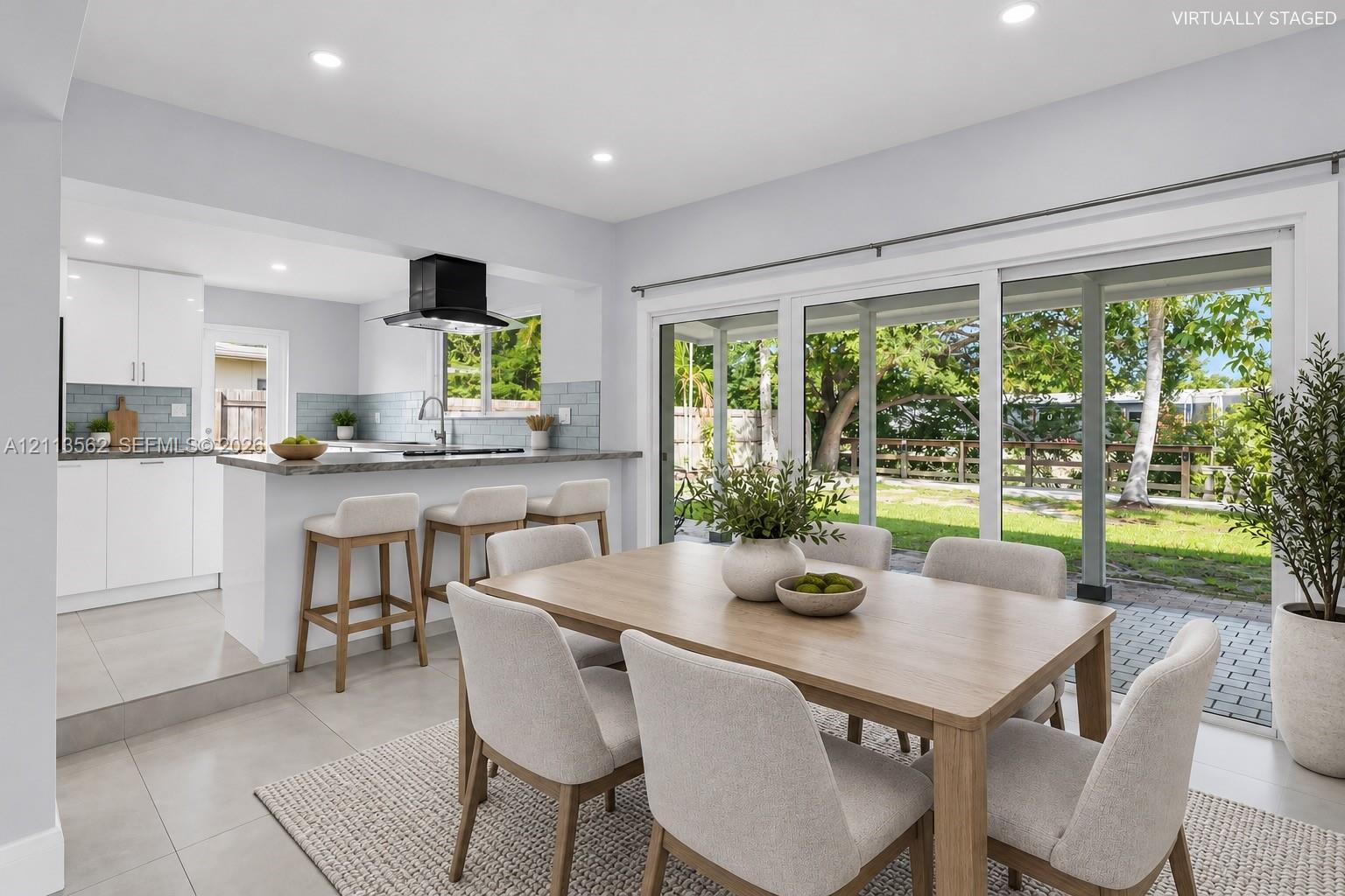 Kitchen featuring a peninsula with countertop seating, tiled backsplash, recessed lighting, and sliding glass doors leading to a paved patio
