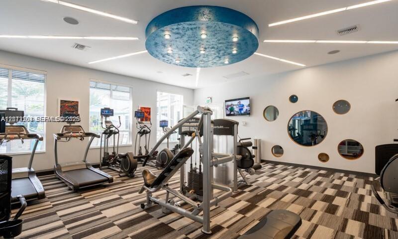 Large-scale circular ceiling feature with recessed lighting, linear LED ceiling accents, multi-paneled windows, circular wall cutouts, and modular flooring tiles