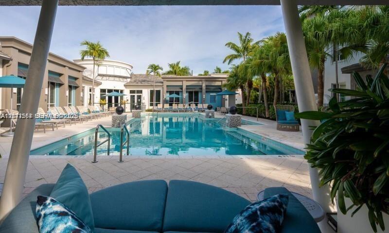 Swimming pool with tiled decking, structural columns, and surrounding palm trees
