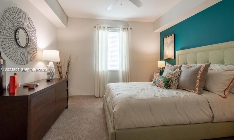 Bedroom featuring a teal accent wall, neutral carpeting, and a ceiling-mounted fan
