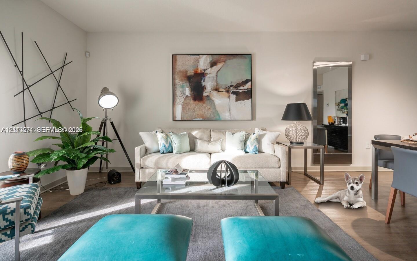 Living area featuring neutral wall tones, full-length mirror, and wood-finish flooring