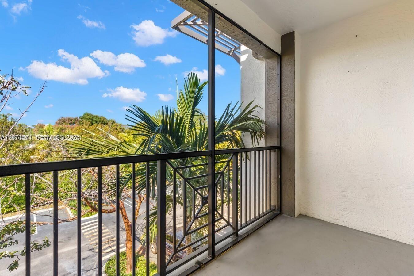 Covered balcony featuring a screened-in enclosure, metal railings with geometric detailing, and a smooth-finish concrete floor