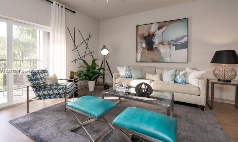 Sliding glass door with access to a balcony, neutral wall tones, and wood-finish flooring