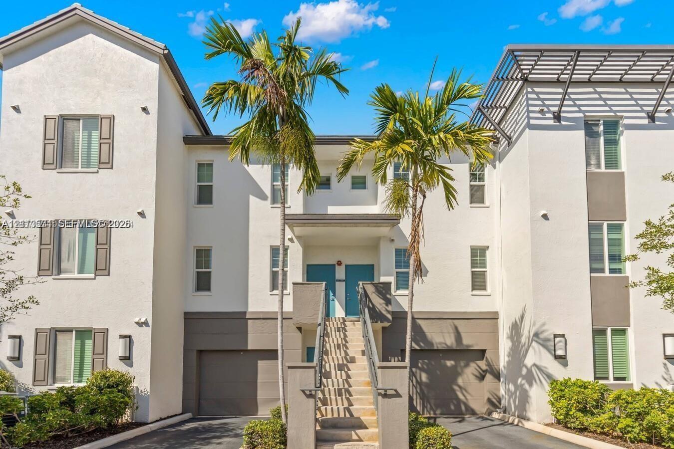 Multi-level stucco exterior featuring integrated dual-car garages, a central staircase with decorative railings, and contemporary window shutters