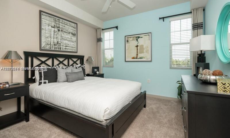 Neutral-toned carpeting, two windows with horizontal blinds, and a ceiling fan