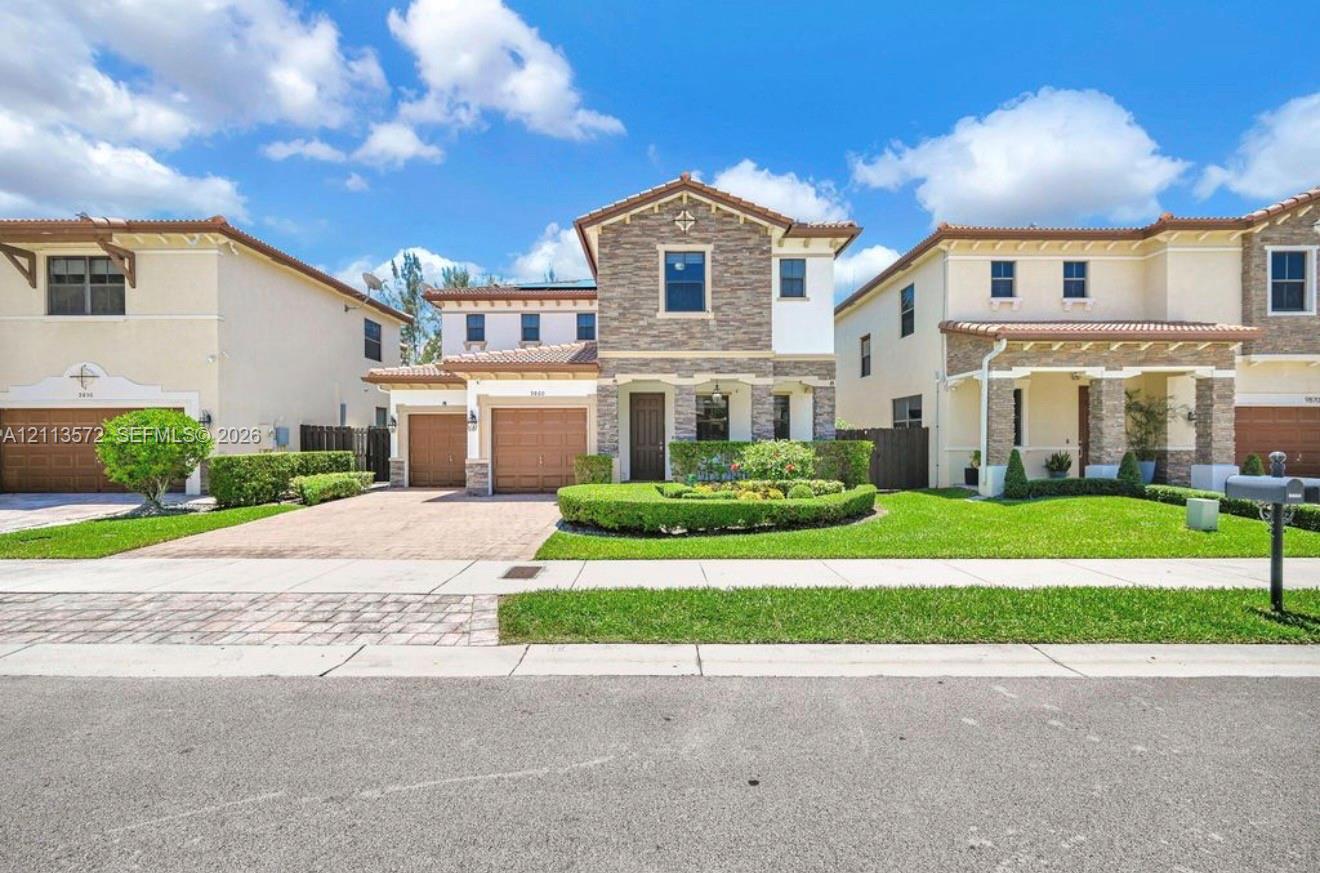 Two-story residence featuring a stone-veneer faade, clay tile roof, dual-car garage, and a manicured front lawn