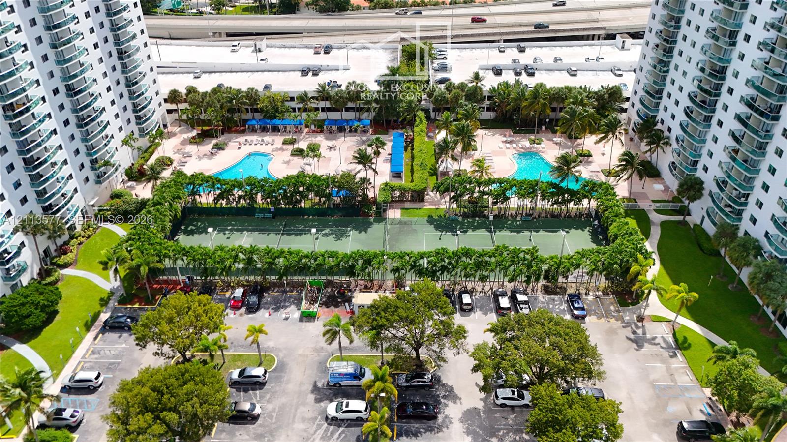 High-rise community featuring dual outdoor swimming pools, multi-court tennis facilities, paved parking, and landscaped grounds