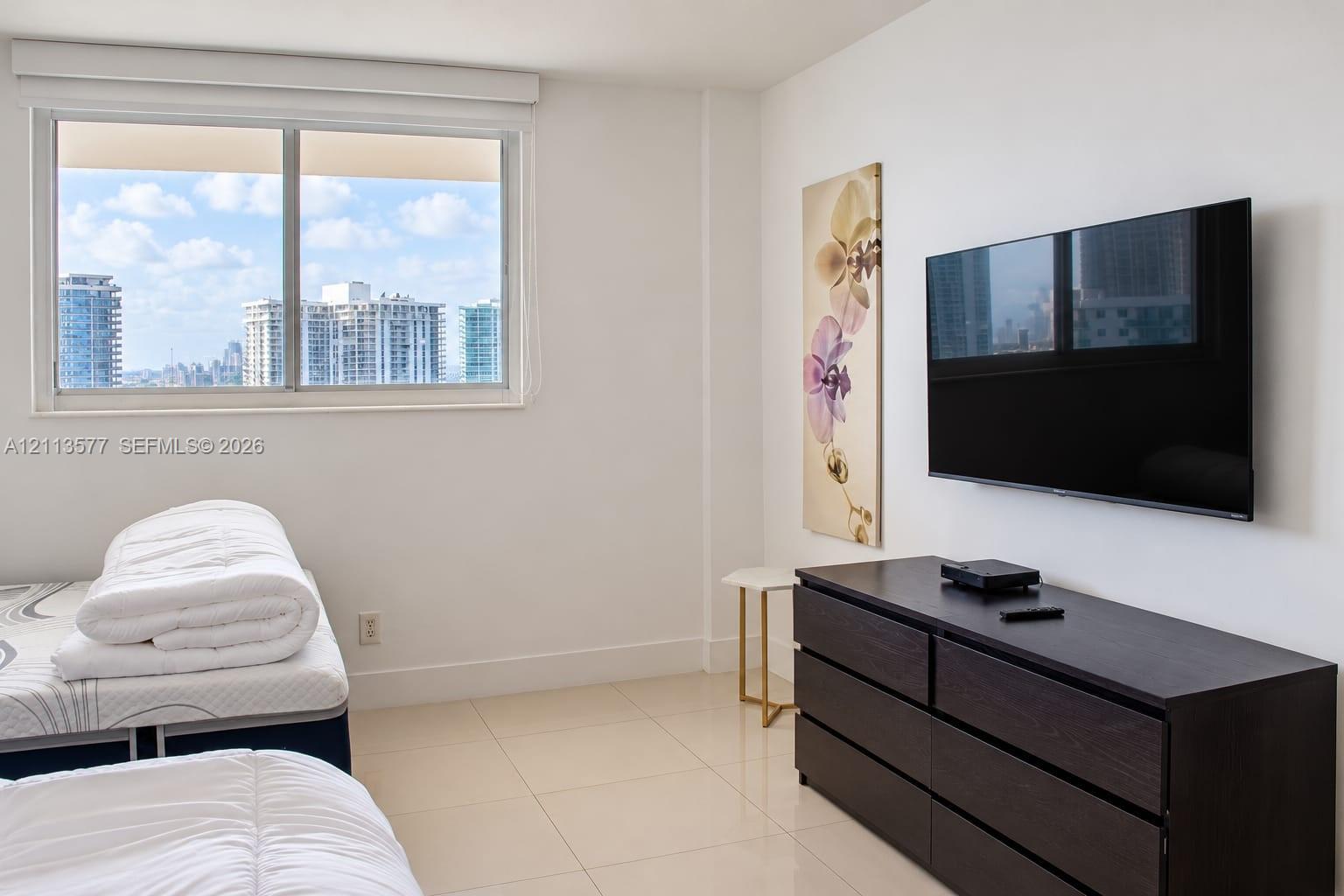 Large-format tile flooring, expansive window with city skyline, and neutral wall finishes