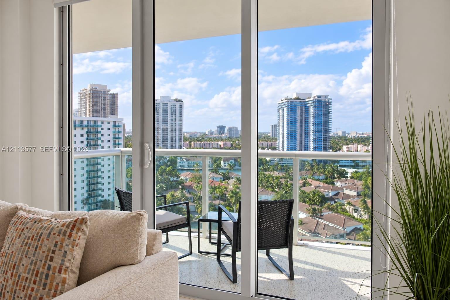 Full-height sliding glass doors with white framing and a private balcony featuring a glass-panel railing Full-height sliding glass doors with white framing and a private balcony featuring a glass-panel railing