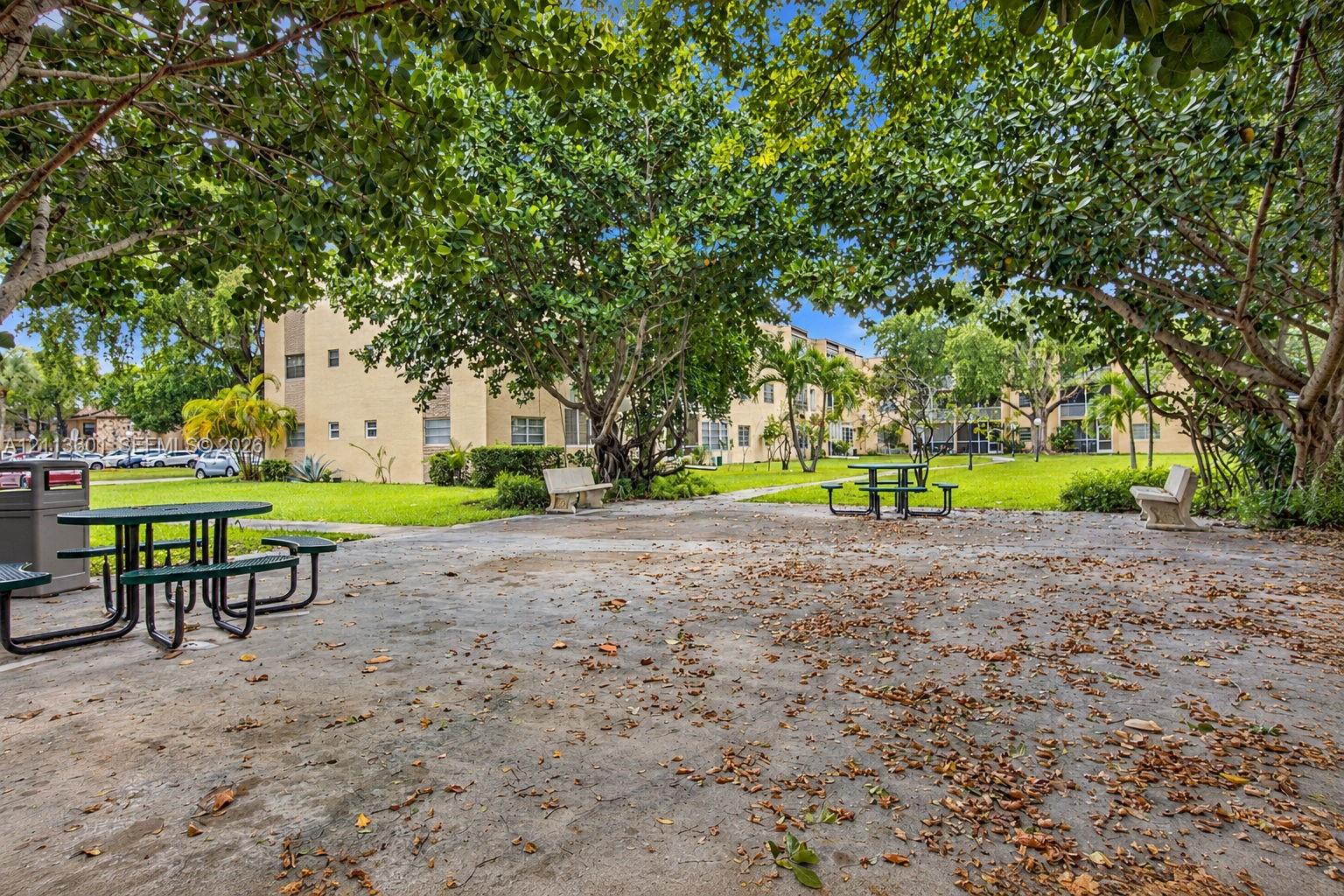 Common area grounds featuring a concrete courtyard, mature shade trees, and built-in stone benches
