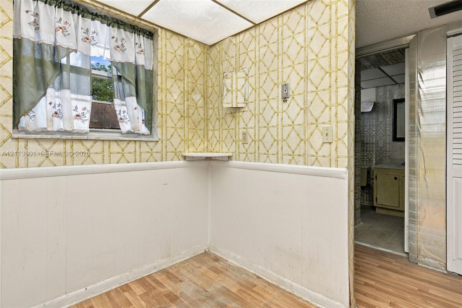 Wood-finish flooring, half-wall wainscoting, integrated corner shelving, recessed ceiling lighting, and louvered closet doors
