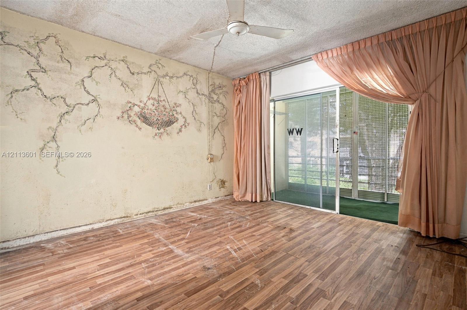 Wood-finish flooring, ceiling fan with light fixture, and floor-to-ceiling sliding glass doors providing outdoor access